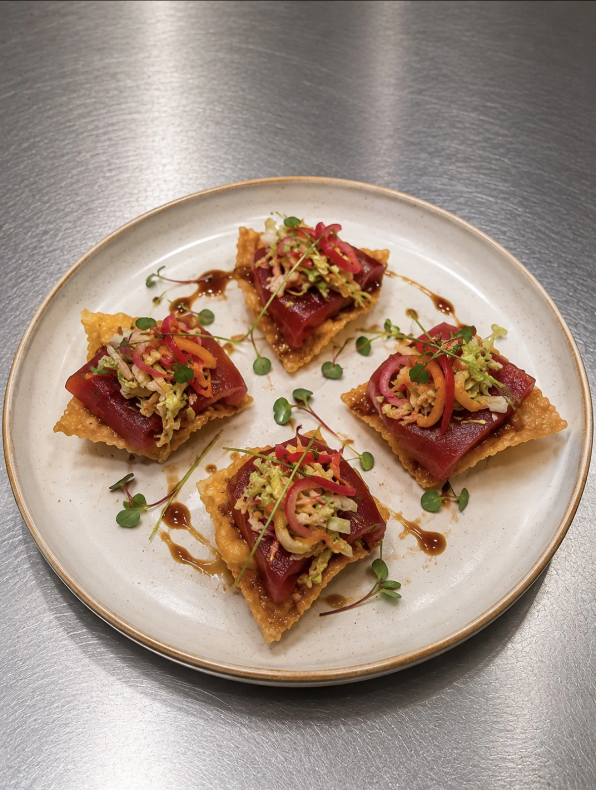 Bluefin tuna crudo on crispy wontons with peach slaw, lime crema, and microgreens.