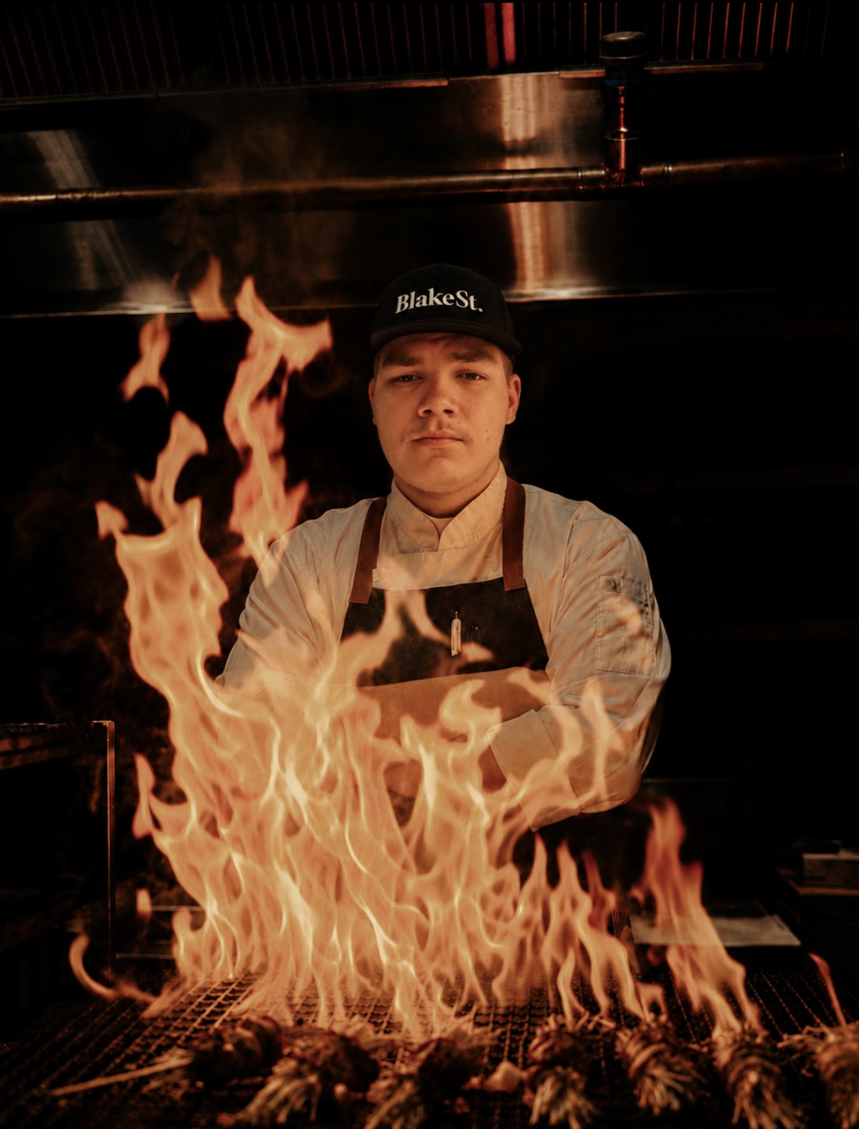 Chef Colby standing behind the fire grill at BlakeSt.