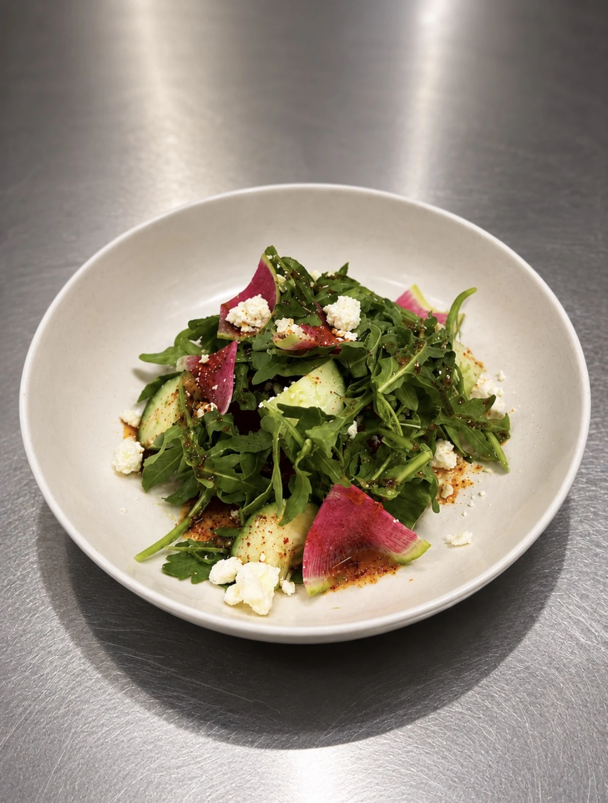 Compressed watermelon salad with cucumber, arugula, feta, radish, and Tajín vinaigrette.