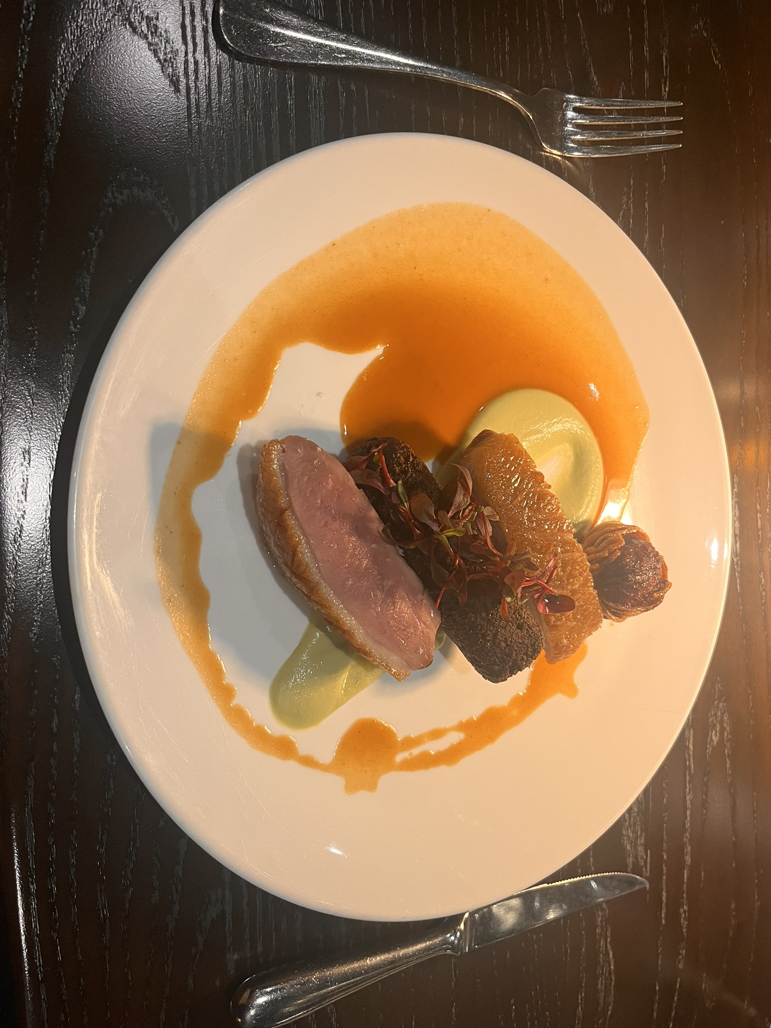 Duck breast with apple cider reduction, pea purée, and microgreens