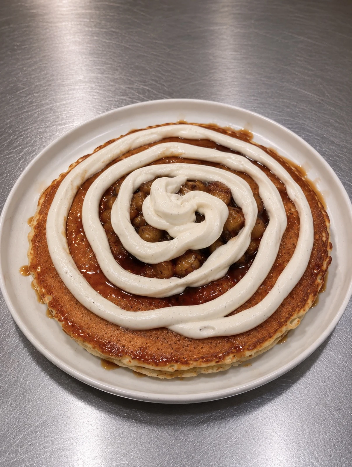 Three banana foster pancakes topped with caramelized bananas, sauce, and Chantilly cream.