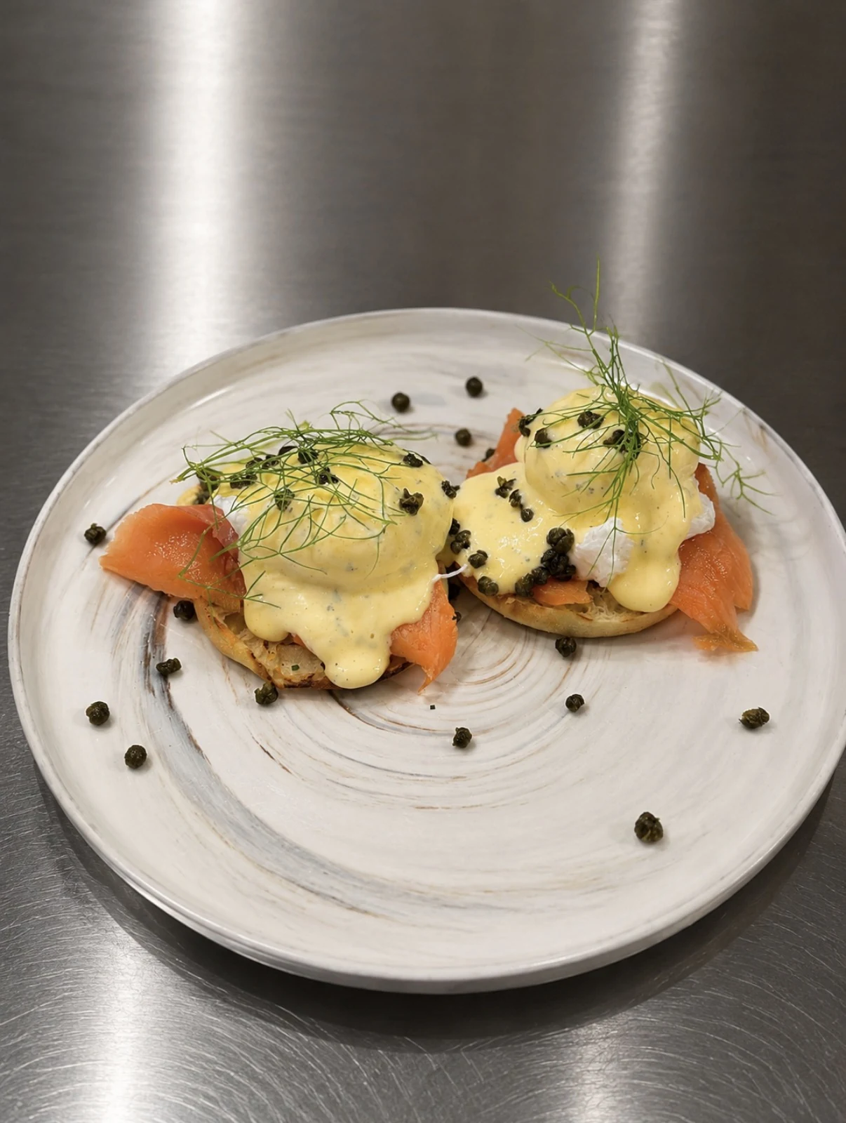 Smoked Scottish salmon Benedict with poached eggs, hollandaise, crispy capers, and fennel fronds.