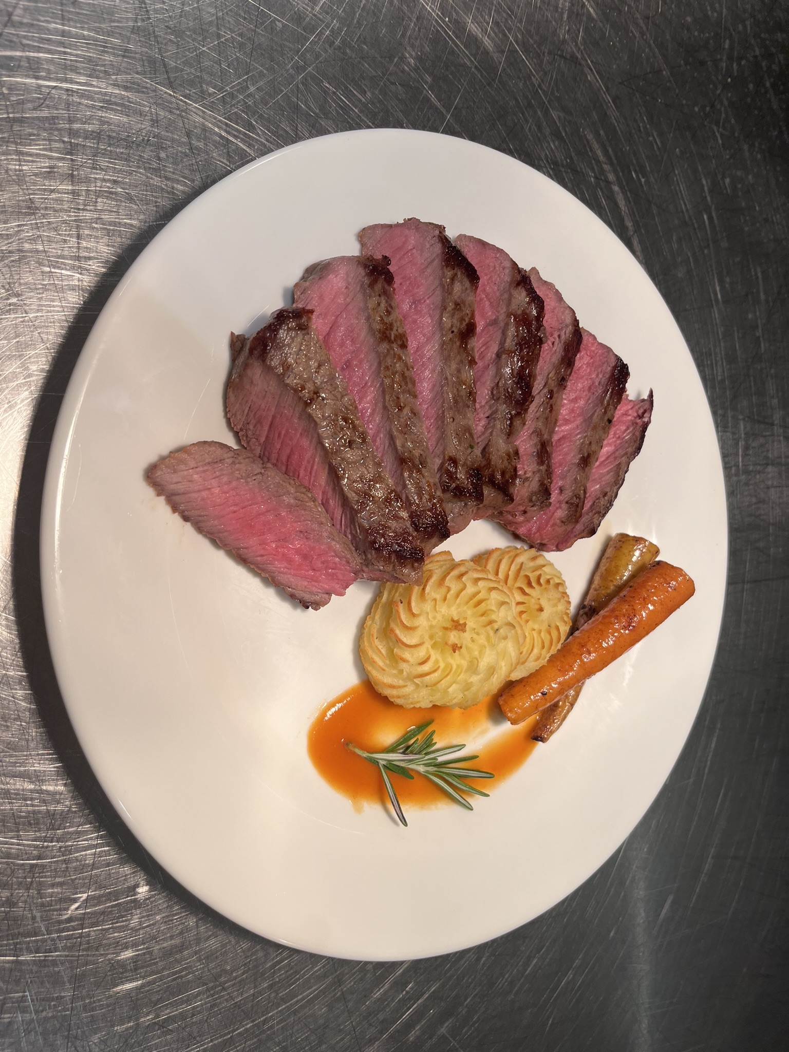 Sliced steak with duchess potatoes, carrots, and vegetable purée