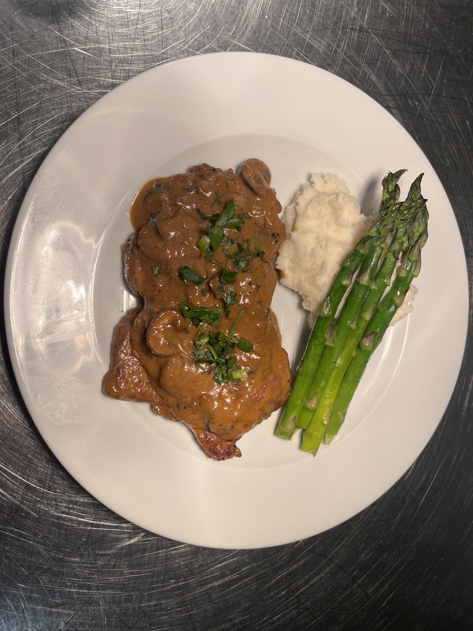 Steak with mushroom sauce, mashed potatoes, and asparagus
