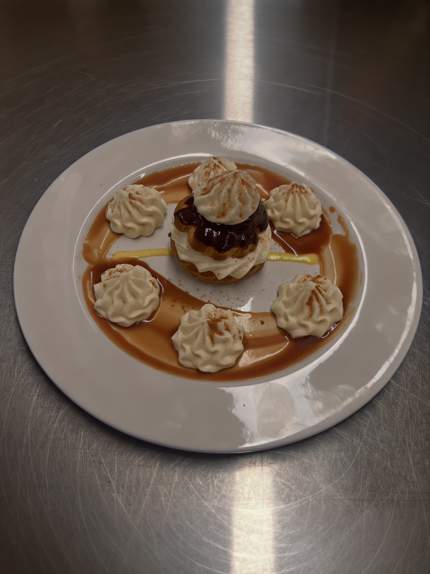 Profiterole layered with vanilla-bean Chantilly cream and chocolate, plated with caramel sauce and crème anglaise.